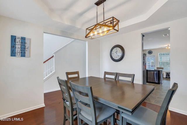 dining room featuring visible vents, baseboards, stairs, dark wood-style floors, and a tray ceiling