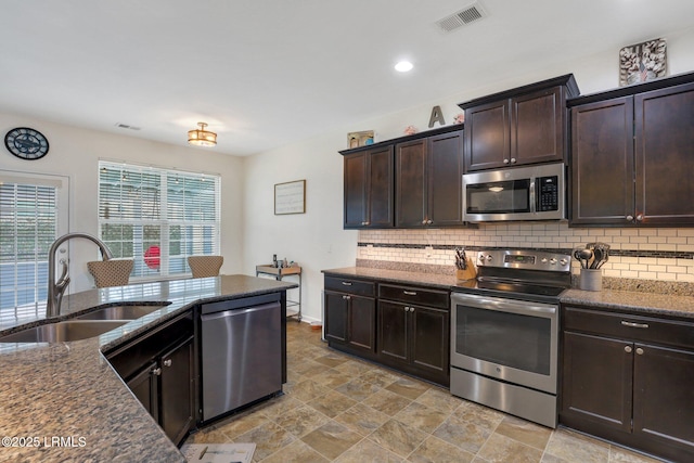 kitchen with a sink, visible vents, dark brown cabinets, appliances with stainless steel finishes, and tasteful backsplash