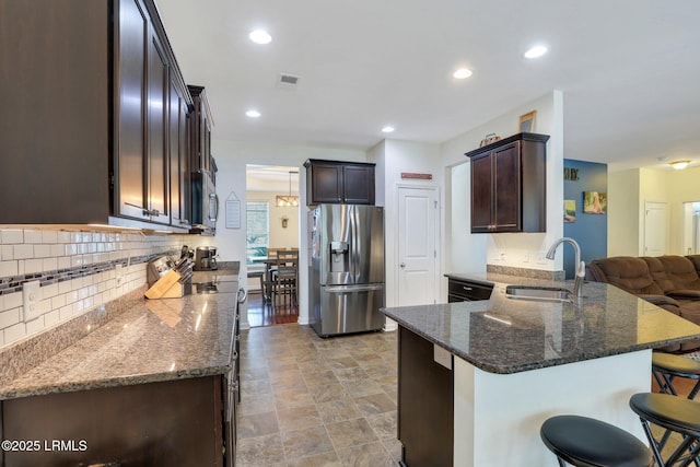 kitchen with tasteful backsplash, visible vents, appliances with stainless steel finishes, a sink, and dark stone counters