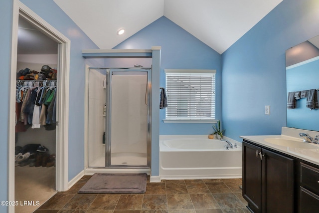 bathroom featuring lofted ceiling, a stall shower, a spacious closet, and a garden tub