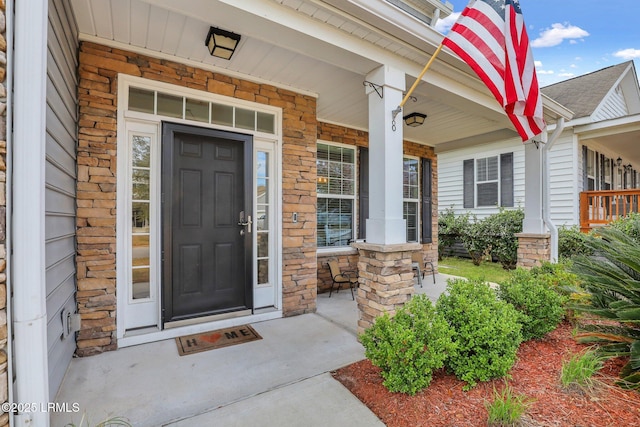 doorway to property featuring stone siding and covered porch