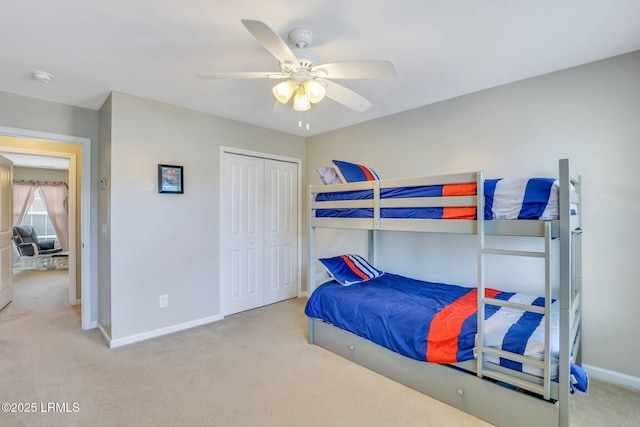 bedroom featuring baseboards, ceiling fan, a closet, and light colored carpet