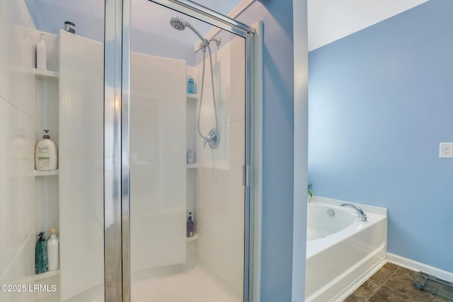 bathroom featuring a shower stall, baseboards, and a bath