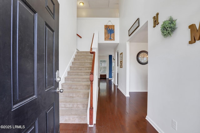 foyer entrance featuring a towering ceiling, stairs, baseboards, and dark wood-type flooring