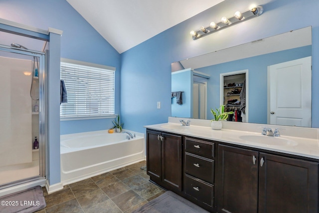 bathroom featuring lofted ceiling, a garden tub, a spacious closet, a shower stall, and a sink