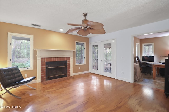 7 Stillwater Ct, Hilton Head Island, SC 29926 - living room with french doors, ceiling fan, wood finished floors, a fireplace, and a textured ceiling