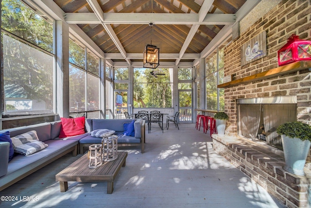 sunroom / solarium featuring a healthy amount of sunlight, a brick fireplace, and vaulted ceiling with beams