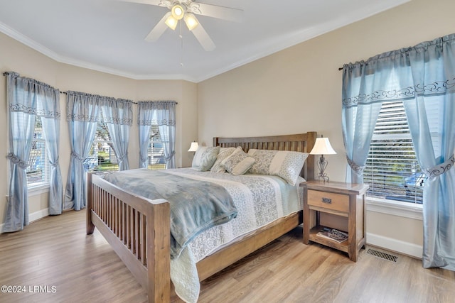 bedroom featuring multiple windows, ornamental molding, ceiling fan, and light wood-type flooring