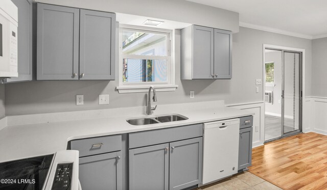 kitchen featuring sink, white appliances, gray cabinetry, ornamental molding, and light wood-type flooring