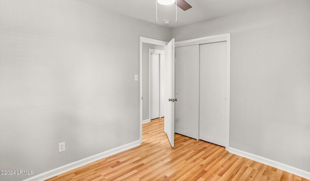 unfurnished bedroom with light wood-type flooring, ceiling fan, and a closet