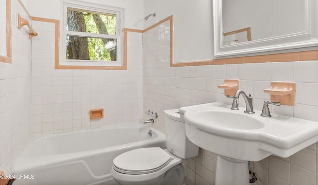 bathroom featuring tiled shower / bath, toilet, and tile walls