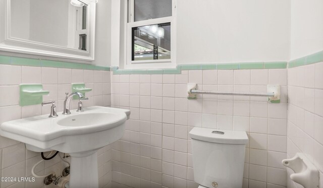 bathroom featuring toilet and tile walls