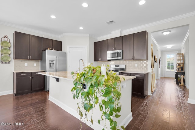 214 Lombards Mill Ln, Okatie, SC 29909 - kitchen with appliances with stainless steel finishes, dark wood finished floors, a center island with sink, visible vents, and dark brown cabinets