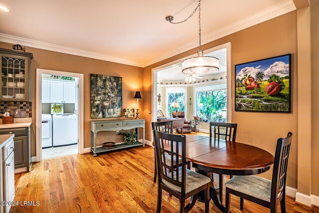 dining space with ornamental molding, washing machine and clothes dryer, and light wood-type flooring