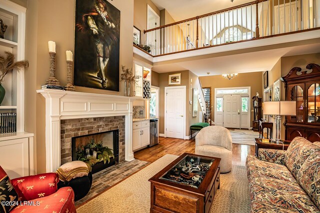 living room with light wood-type flooring, a fireplace, built in features, and a high ceiling