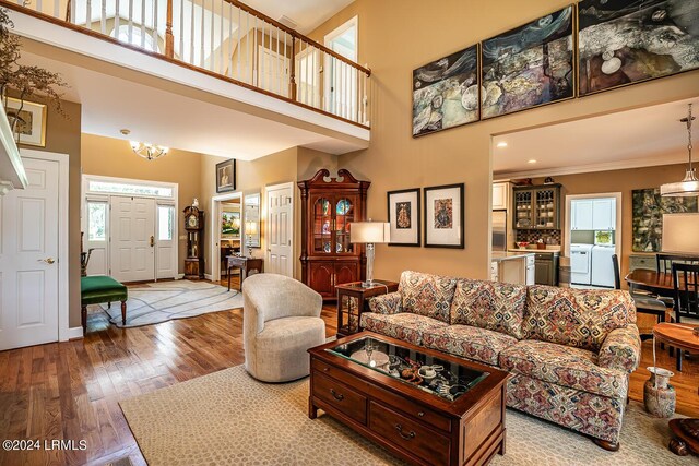 living room with a towering ceiling, wood-type flooring, and washer and clothes dryer