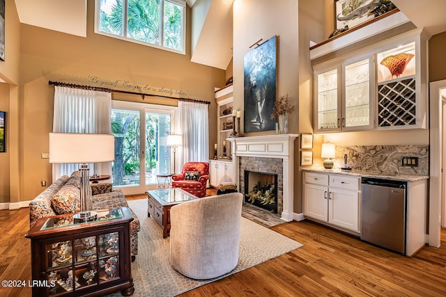 living room featuring a high ceiling, a brick fireplace, bar, and light hardwood / wood-style floors