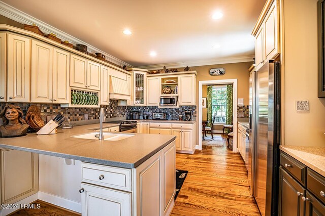 kitchen featuring sink, kitchen peninsula, stainless steel appliances, crown molding, and light hardwood / wood-style flooring