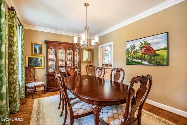 dining room with ornamental molding, hardwood / wood-style floors, and a notable chandelier