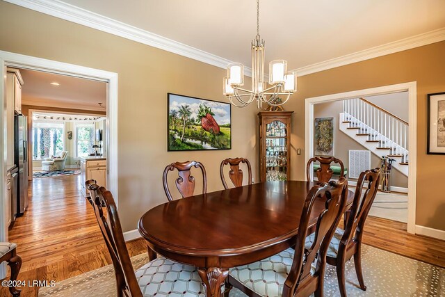 dining space featuring crown molding, a chandelier, and light hardwood / wood-style flooring