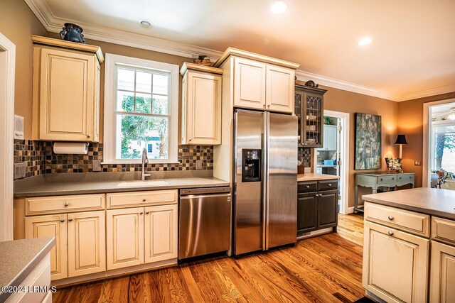 kitchen with sink, decorative backsplash, light hardwood / wood-style floors, stainless steel appliances, and cream cabinets