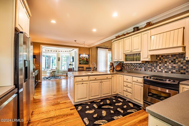 kitchen featuring sink, hanging light fixtures, kitchen peninsula, stainless steel appliances, and light hardwood / wood-style flooring