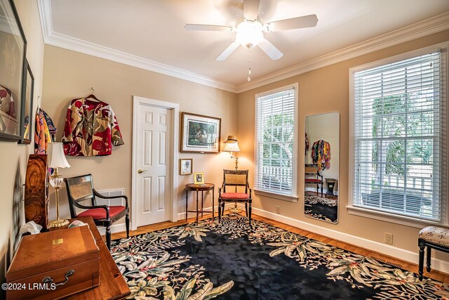 living area with ceiling fan, crown molding, wood-type flooring, and a healthy amount of sunlight