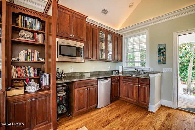 kitchen with stainless steel appliances, sink, dark stone countertops, and light hardwood / wood-style flooring