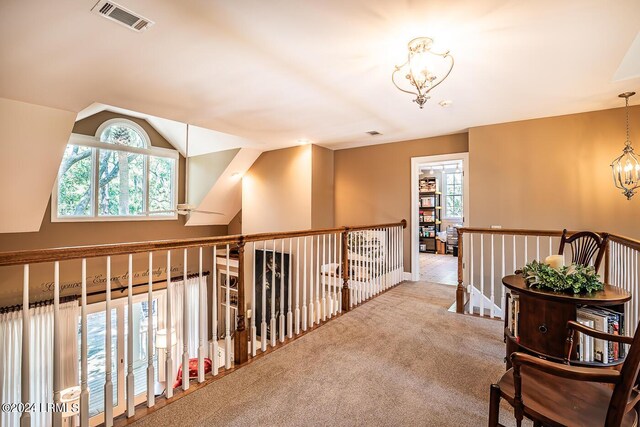 hall featuring an inviting chandelier and light carpet