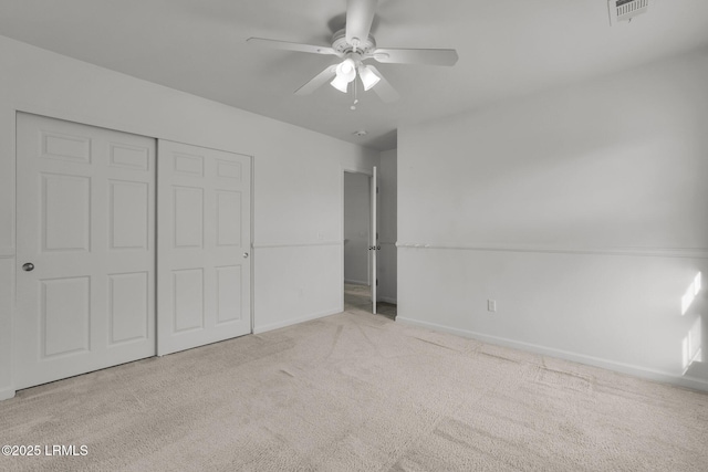 unfurnished bedroom with ceiling fan, light carpet, and a closet