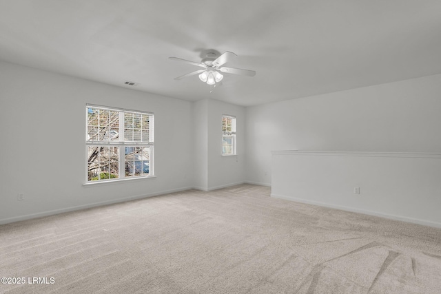 unfurnished room with ceiling fan, light colored carpet, and plenty of natural light