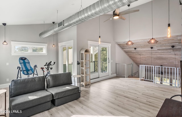 living room with light wood-type flooring, ceiling fan, and a high ceiling