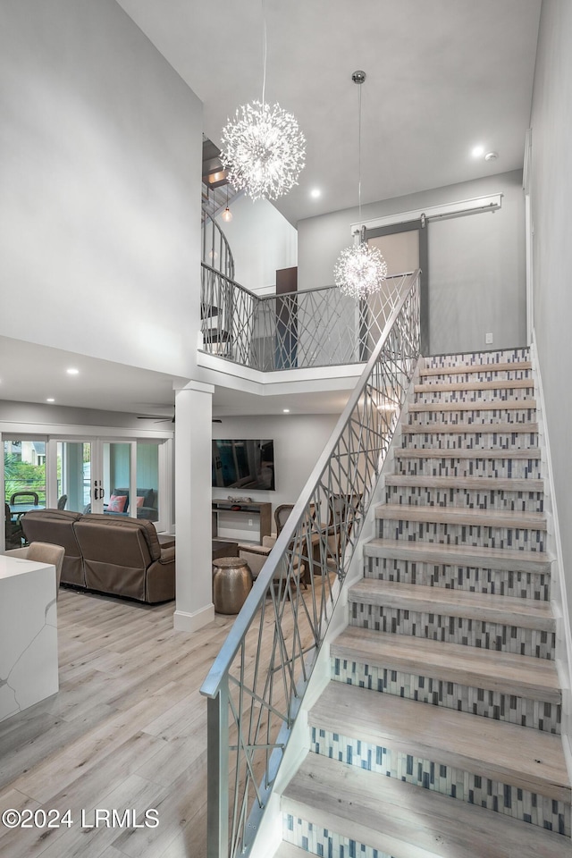 staircase with hardwood / wood-style flooring, a chandelier, and a high ceiling