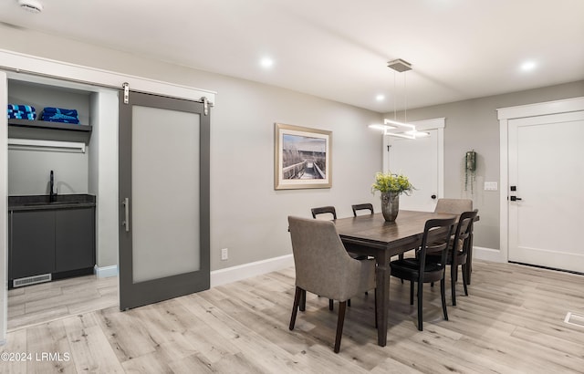 dining space featuring a barn door, sink, and light wood-type flooring