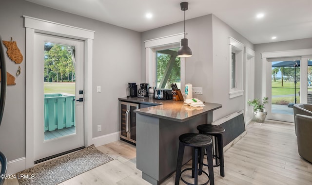 kitchen with hanging light fixtures, light wood-type flooring, a kitchen breakfast bar, and kitchen peninsula