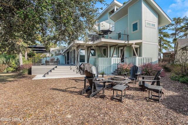 rear view of property featuring a balcony and a fire pit