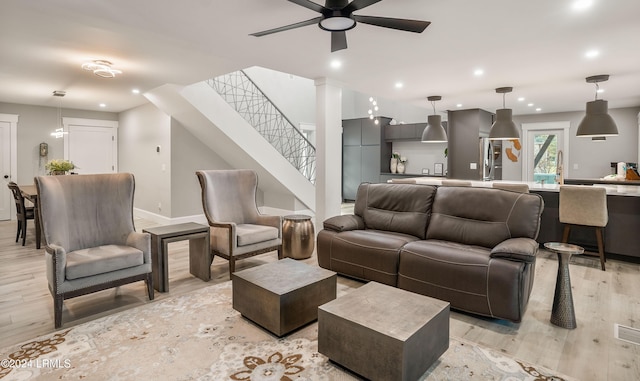 living room with light hardwood / wood-style flooring, decorative columns, and ceiling fan