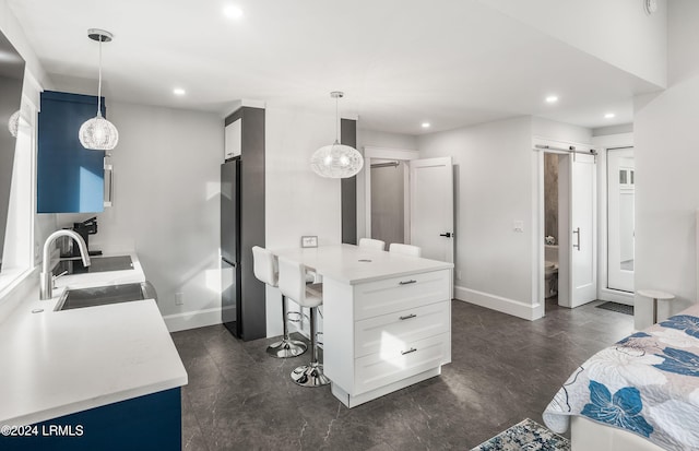 bedroom featuring sink, fridge, a barn door, and ensuite bathroom