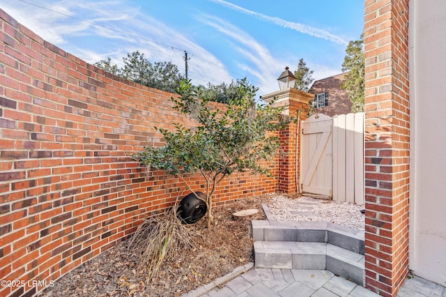 exterior space with a gate, a fenced backyard, and brick siding