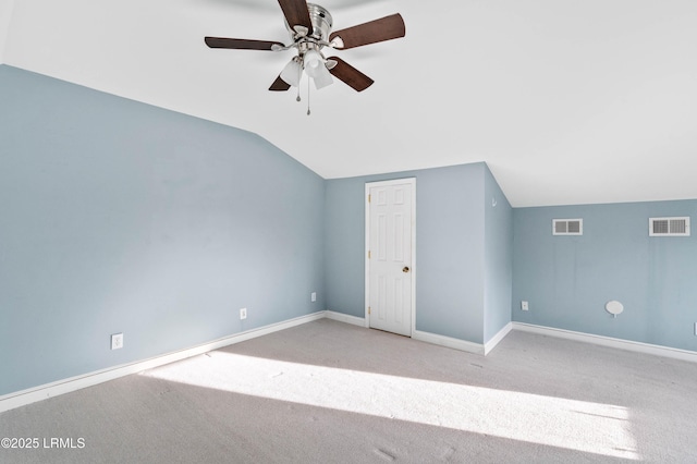 additional living space with light carpet, baseboards, visible vents, and vaulted ceiling