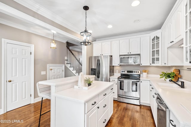 kitchen featuring light countertops, appliances with stainless steel finishes, glass insert cabinets, and a center island