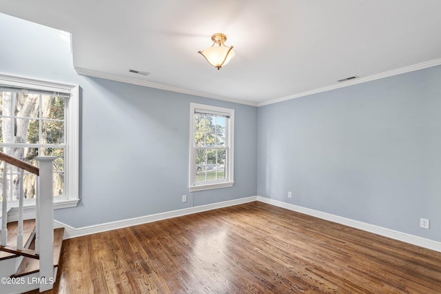 unfurnished room with visible vents, crown molding, baseboards, and wood finished floors