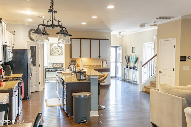 kitchen with sink, a kitchen island with sink, stainless steel appliances, dark hardwood / wood-style floors, and decorative light fixtures