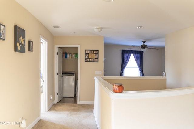 hallway with washer / clothes dryer and light colored carpet