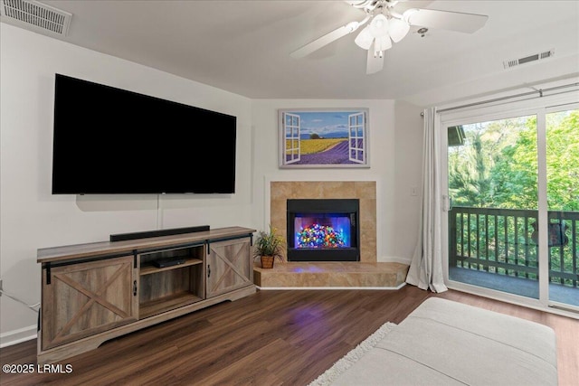 living room featuring dark wood finished floors, ceiling fan, visible vents, and a fireplace