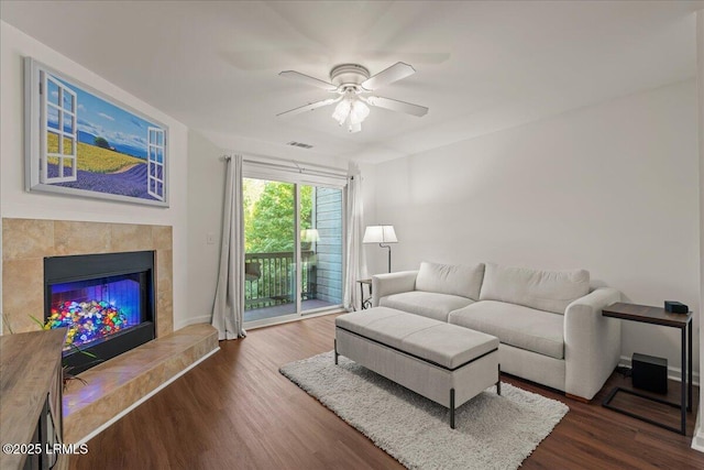 living room with a fireplace, wood finished floors, visible vents, and a ceiling fan