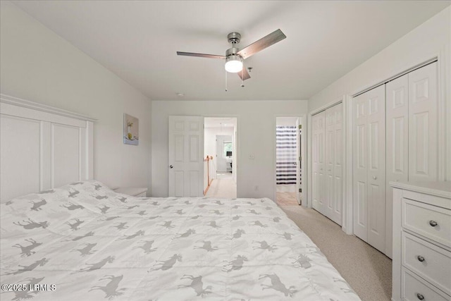 bedroom with ceiling fan, light colored carpet, and two closets