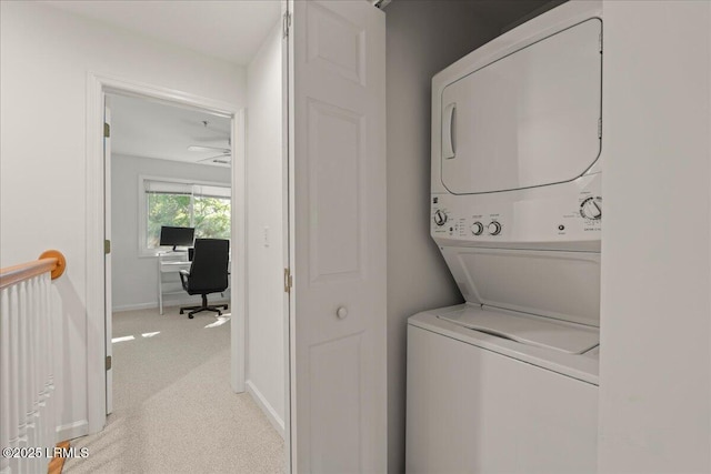 laundry room with stacked washer / drying machine, light colored carpet, baseboards, and laundry area