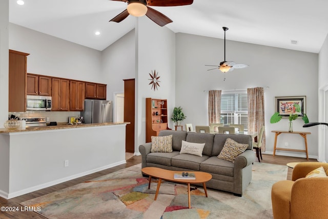 living room with ceiling fan, high vaulted ceiling, and hardwood / wood-style floors