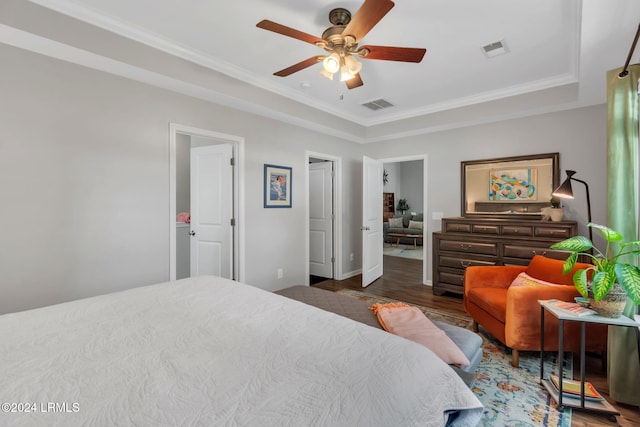 bedroom with crown molding, ceiling fan, dark hardwood / wood-style flooring, and a raised ceiling